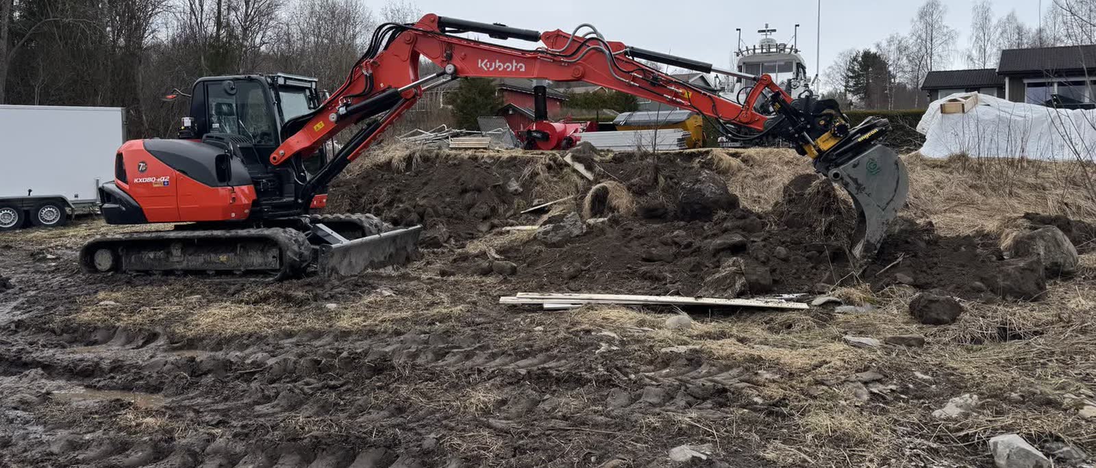 Gravemaskin i arbeid med masser på en tomt