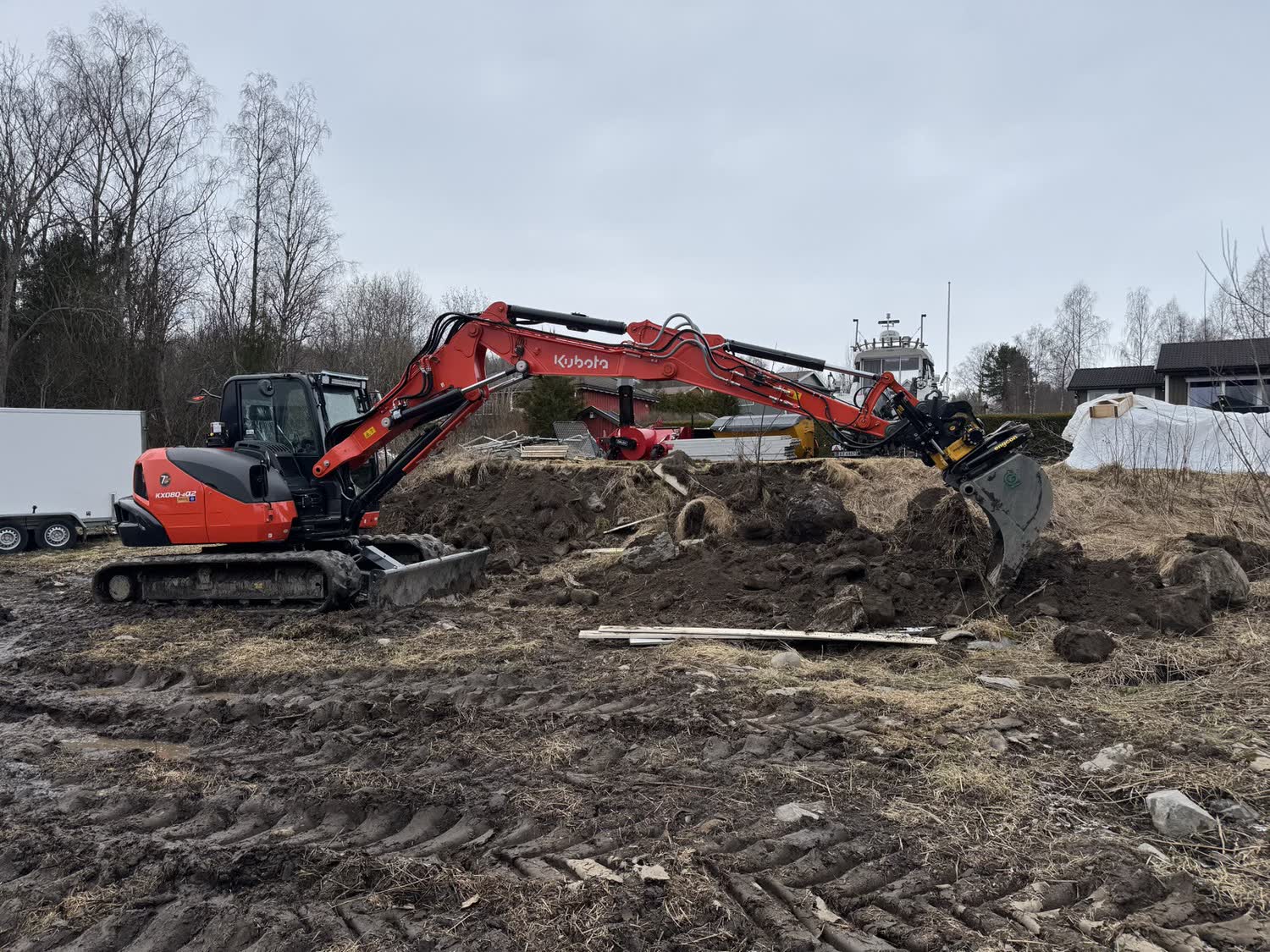 Gravemaskin i arbeid med masser på en tomt