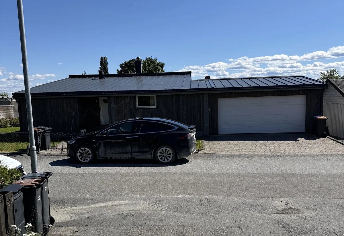 Enebolig med mørk kledning og tilbygd garasje